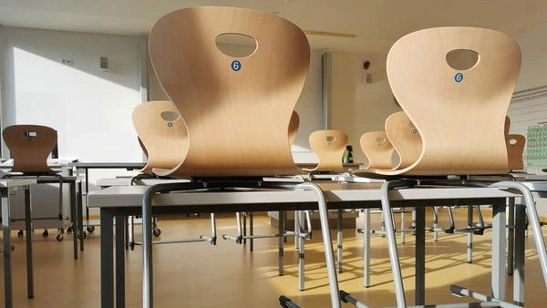 Bild zeigt einen leeren Klassenraum. Die Stühle sind hochgestellt.