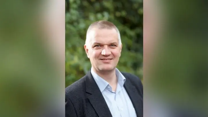 Bild zeigt Prof. Dr. Nils Neuber vor einem grünen Blätterhintergrund.