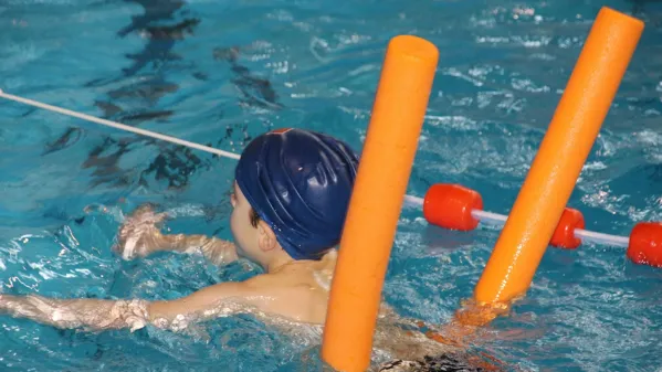 Bild zeigt einen Jungen beim Schwimmen mit einer Noodle.