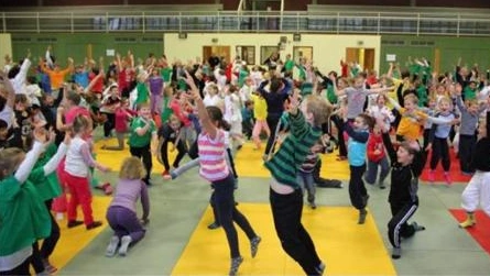Bild zeigt zwei Judoka im Kampf vor anderen Athletinnen und Athleten.