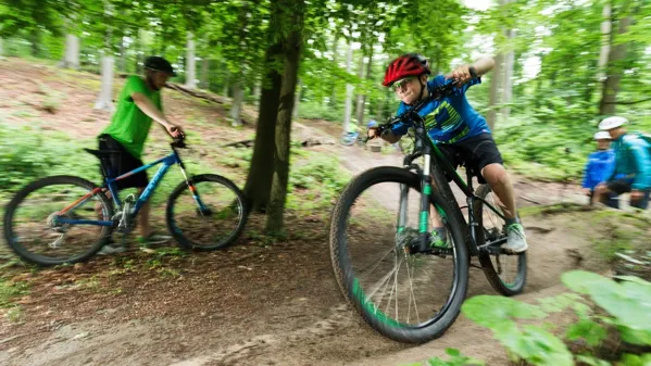 Bild zeigt Schüler mit dem Mountainbike auf einem Trail im Wald.