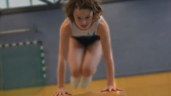 Bild zeigt ein Mädchen beim Hocksprung über einen Kasten.
