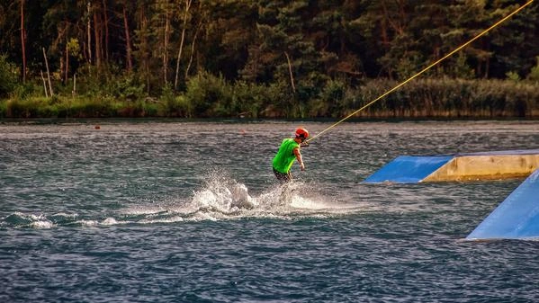 Bild zeigt eine Person beim Wakeboard fahren.