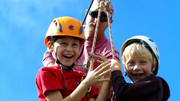 Bild zeigt zwei Kinder, die in eine Zipline einsteigen.